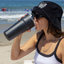 Lady on the beach drinking form a black Splitflask