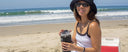 Girl sitting on the beach holding a Splitflask stainless steel water bottle