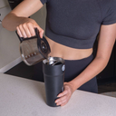 Lady pouring hot coffee into a black Splitflask tumbler